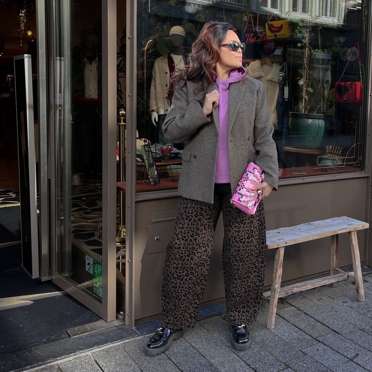 Een wijde broek met een korte blazer erop, voor de etalage van The Hype